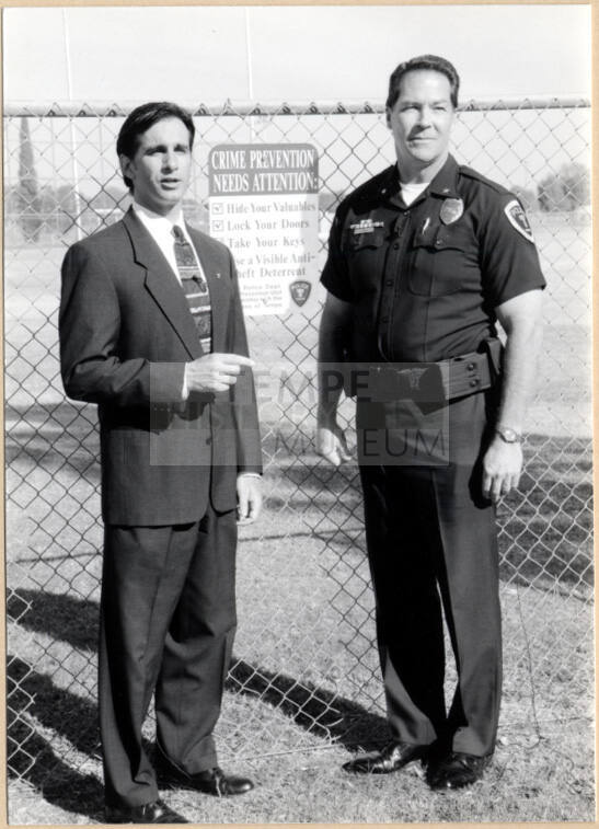 Photo of Neil Giuliano with Police Officer by "Crime Prevention Needs Attention" Sign.