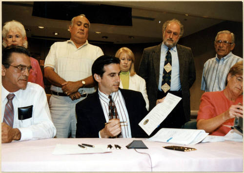 Mayor Neil Giuliano Signing a Paper While City Council Looks On.