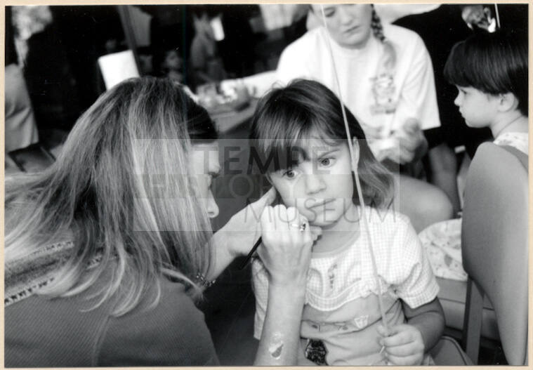 Black and white photograph of face painting of a child at Fire Prevention Day