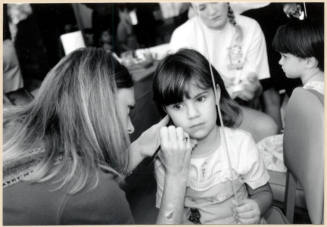 Black and white photograph of face painting of a child at Fire Prevention Day