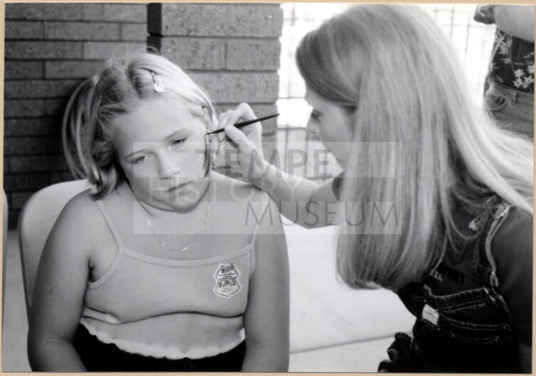 Black and white photograph of girl getting her face painted at Fire Prevention Day