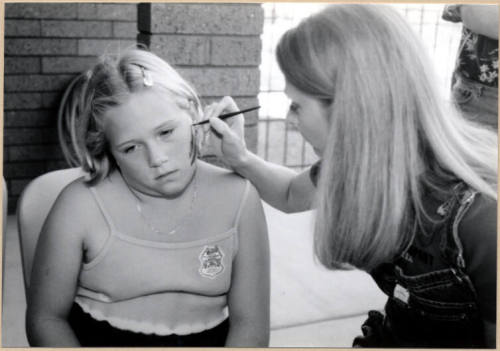 Black and white photograph of girl getting her face painted at Fire Prevention Day