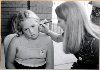 Black and white photograph of girl getting her face painted at Fire Prevention Day
