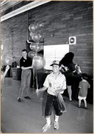 Black and white photograph of Cub Scout holding balloons at Fire Prevention Day