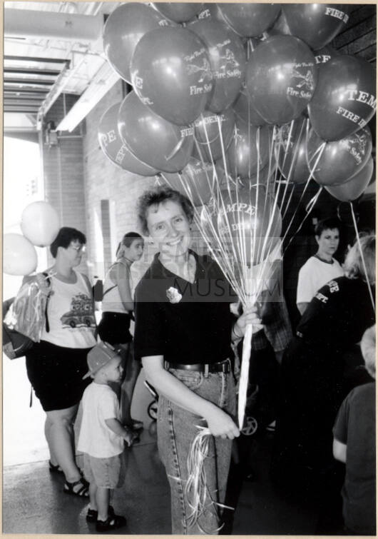 Black and white photograph of firefighter with balloons at Fire Prevention Day