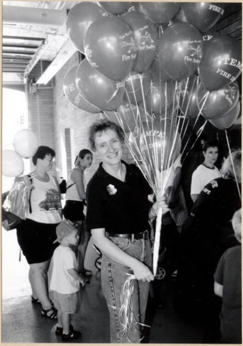 Black and white photograph of firefighter with balloons at Fire Prevention Day