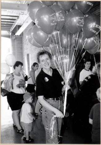 Black and white photograph of firefighter with balloons at Fire Prevention Day