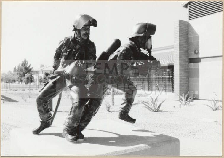 Black and white photograph of statues of fire fighters at the dedication of Apache Blvd. Fire Station