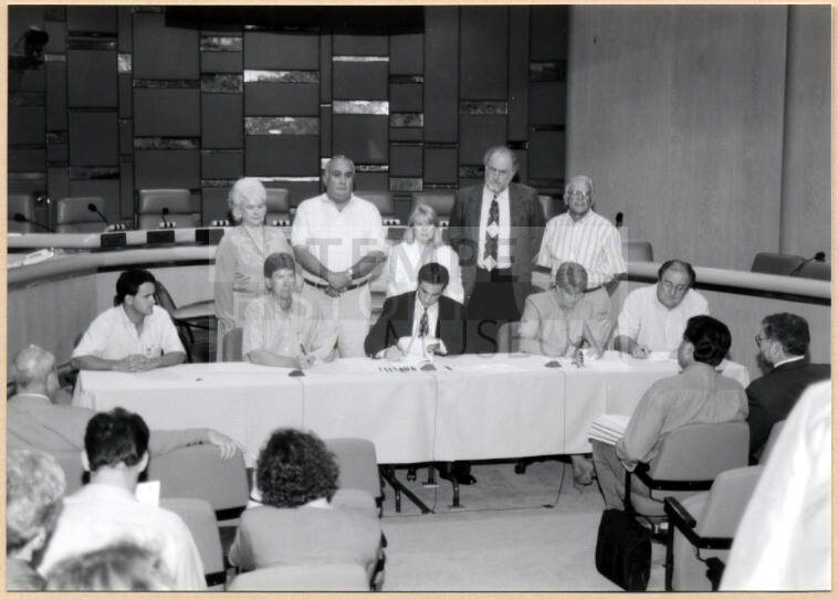 Black and white photograph of Mayor Giuliano and city council signing Town Lake contract in City Council Chambers
