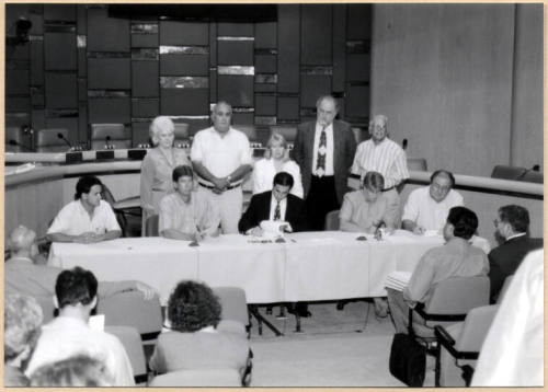Black and white photograph of Mayor Giuliano and city council signing Town Lake contract in City Council Chambers
