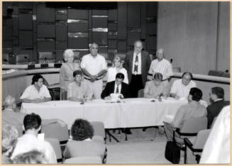 Black and white photograph of Mayor Giuliano and city council signing Town Lake contract in City Council Chambers