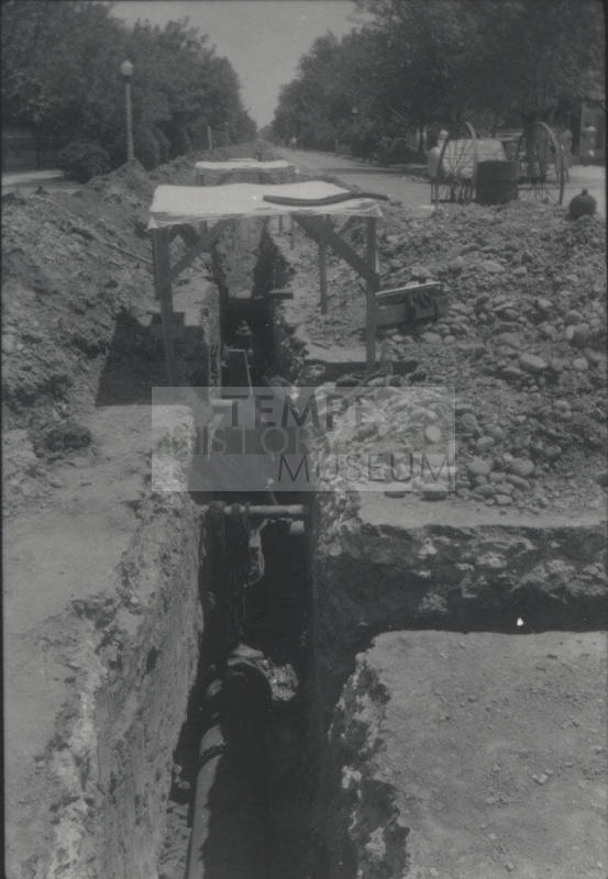 Workmen Lay Pipe in Streetside Trench