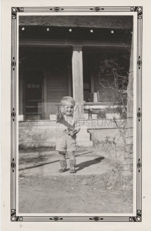 McNeil Boy Standing in Front of a House
