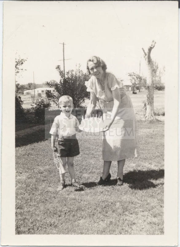Woman Holding a Cake to a Young Boy