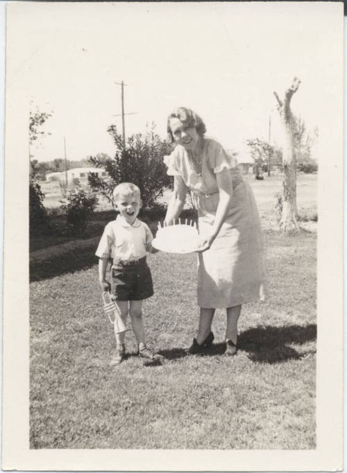 Woman Holding a Cake to a Young Boy