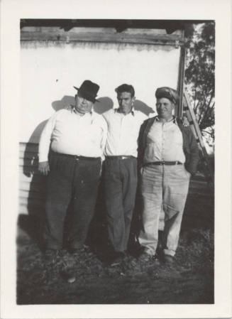 Three Men Standing Against a White Wall
