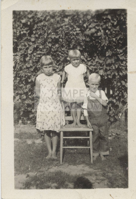Children Standing by and on a Chair