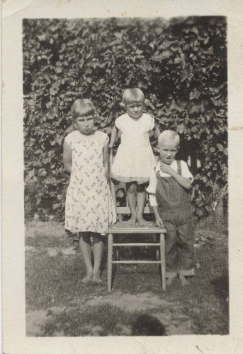 Children Standing by and on a Chair