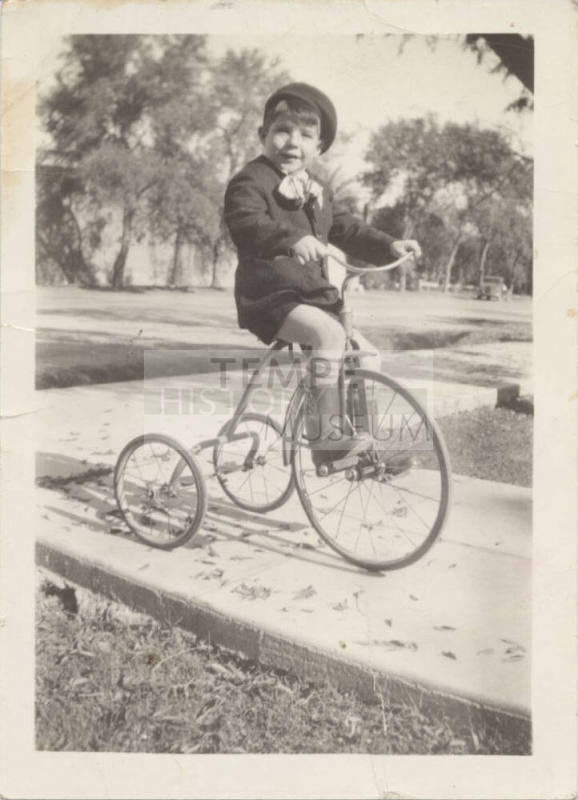 A Boy Riding on a Tricycle in Uniform