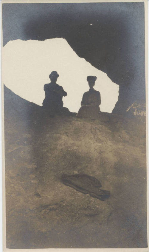 View of People Sitting at Hole in a Rock
