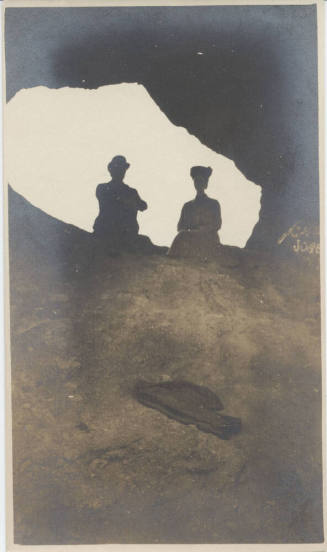 View of People Sitting at Hole in a Rock