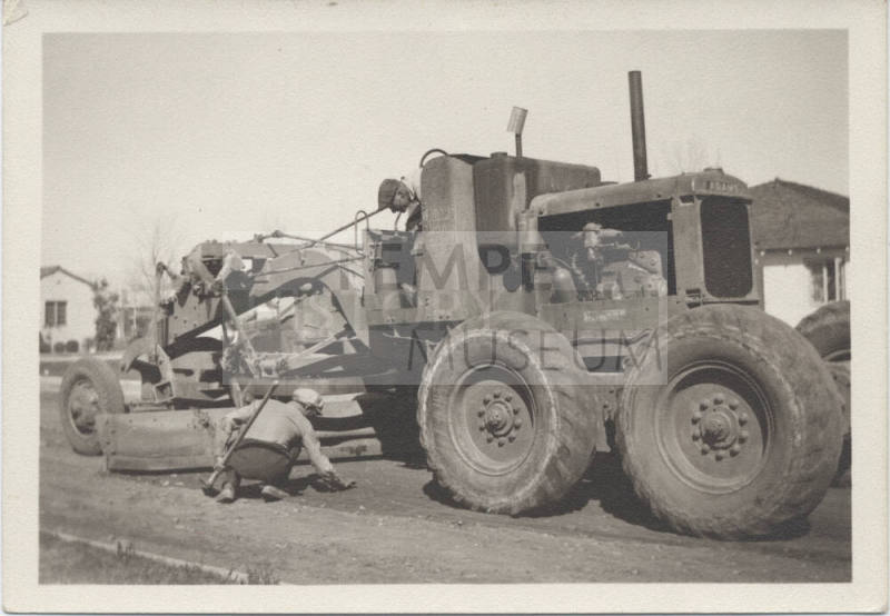 Two men working around road grader