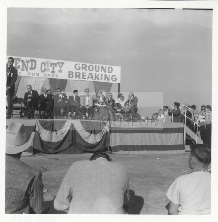 Photograph, people seated on stage at the groundbreaking for Legend City