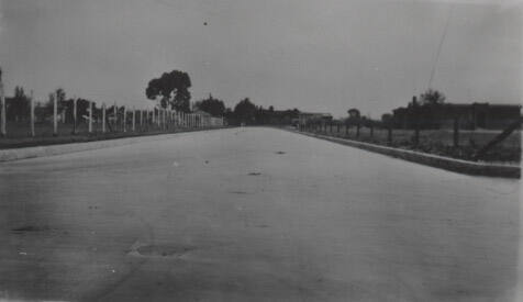 Wide paved road lined with fences