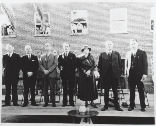 People on a stage as children look on through windows