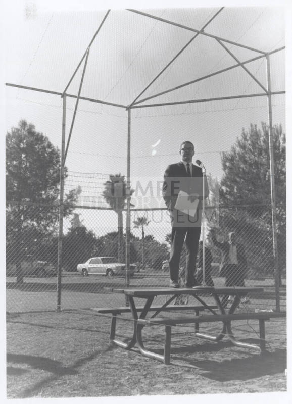 Draft protest march--Man in suit standing on table with microphone