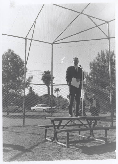 Draft protest march--Man in suit standing on table with microphone