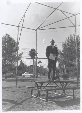 Draft protest march--Man in suit standing on table with microphone
