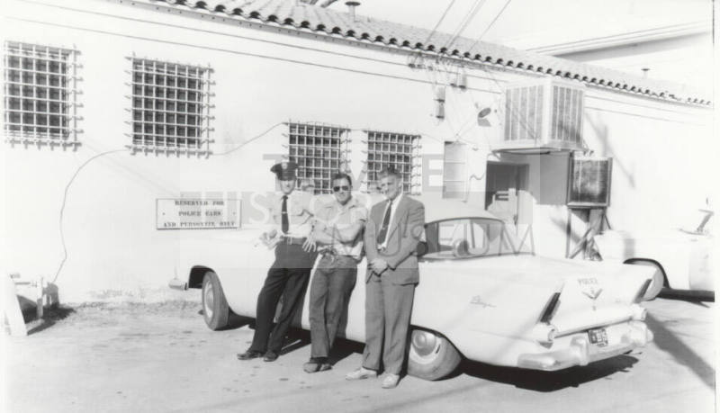 Uniformed police officer and two other men behind the Tempe Police Station.