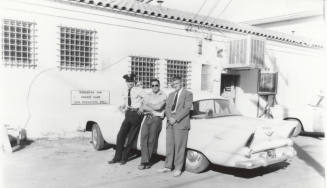 Uniformed police officer and two other men behind the Tempe Police Station.