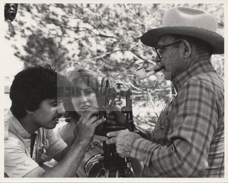 B/W Photo of Luther Finley holding a transit that is being examined by two (2) students.