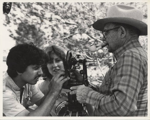 B/W Photo of Luther Finley holding a transit that is being examined by two (2) students.