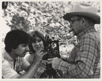 B/W Photo of Luther Finley holding a transit that is being examined by two (2) students.