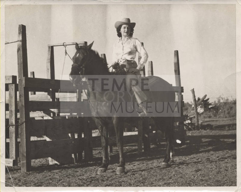 B/W Photo of a Woman on a Horse by a Farm Fence