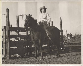 B/W Photo of a Woman on a Horse by a Farm Fence
