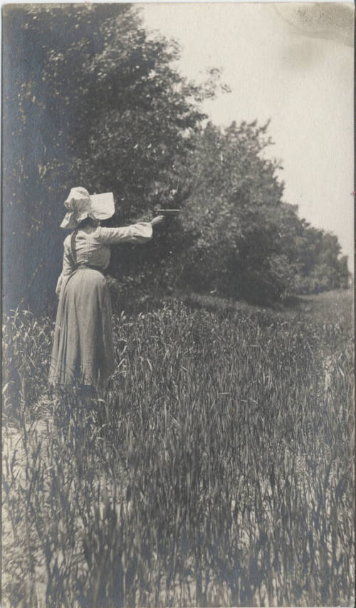 Woman Standing in Field Shooting Firearm