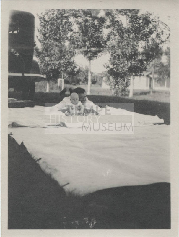 Adult and Child on Blanket Behind Car