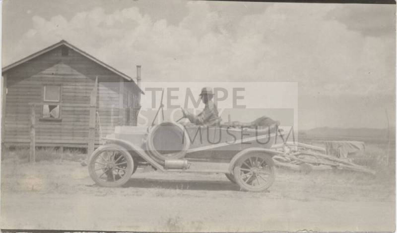 Man Driving Open Car on Road by Dwelling