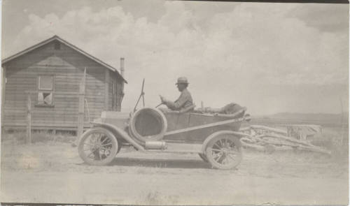 Man Driving Open Car on Road by Dwelling