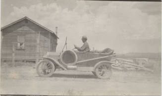 Man Driving Open Car on Road by Dwelling