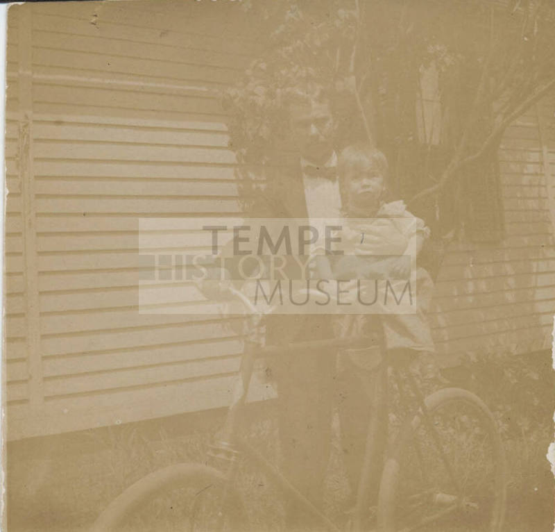 Man Holding Child Beside Bicycle