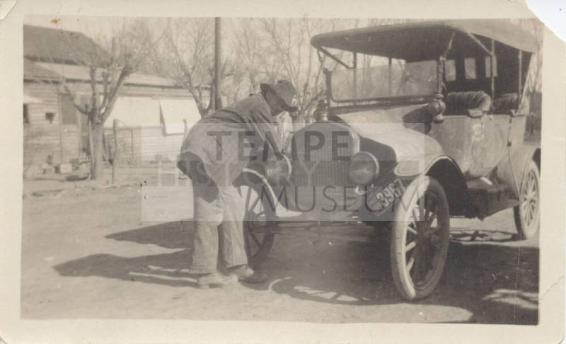 Man Leaning on Car Fender Near House