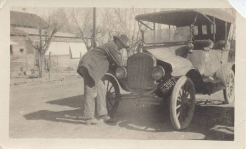 Man Leaning on Car Fender Near House