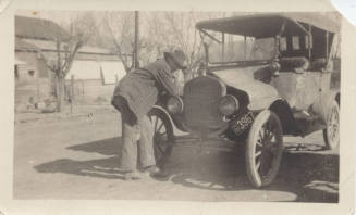 Man Leaning on Car Fender Near House