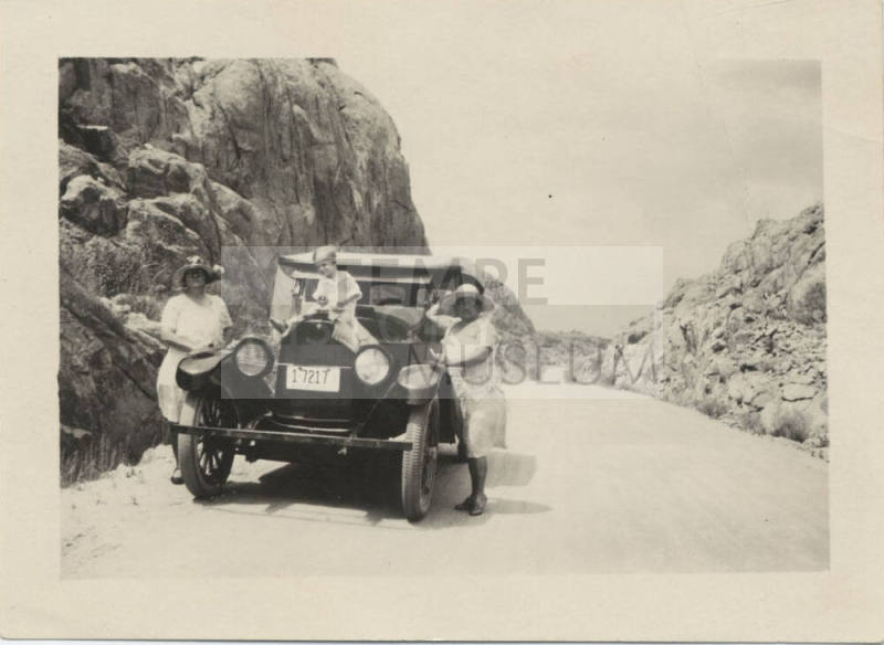 Two Women and Boy by Parked Car on Road