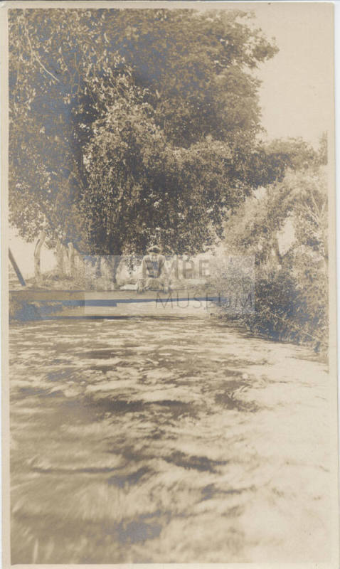 Woman Sitting on Bridge Over Canal